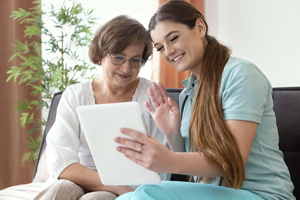 nurse helping an elderly woman on tablet with primary care services from VitaVia Telemedicine